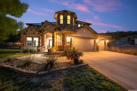 La Cantera - dusk exterior of a stone and stucco home with a turret