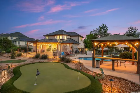 La Cantera - twilight backyard with a putting green and covered outdoor kitchen