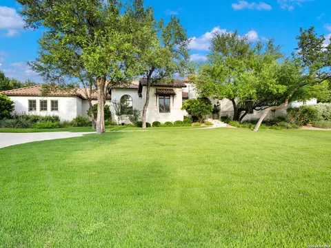 Shavano Park - front exterior of a Spanish-style stucco home with an expansive lawn