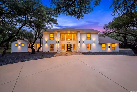 Shavano Park - dusk exterior of a modern white stucco home with a circular drive