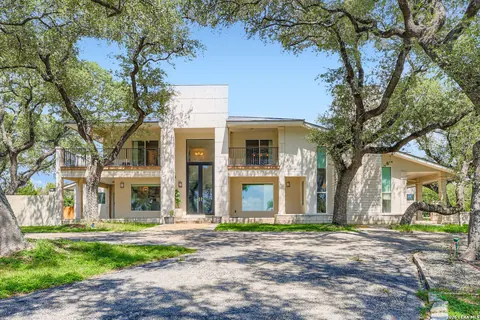 Hill Country Village - front exterior of a modern home shaded by oak trees